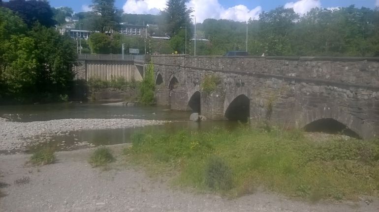 Low level river flowing under a bridge with multiple arches