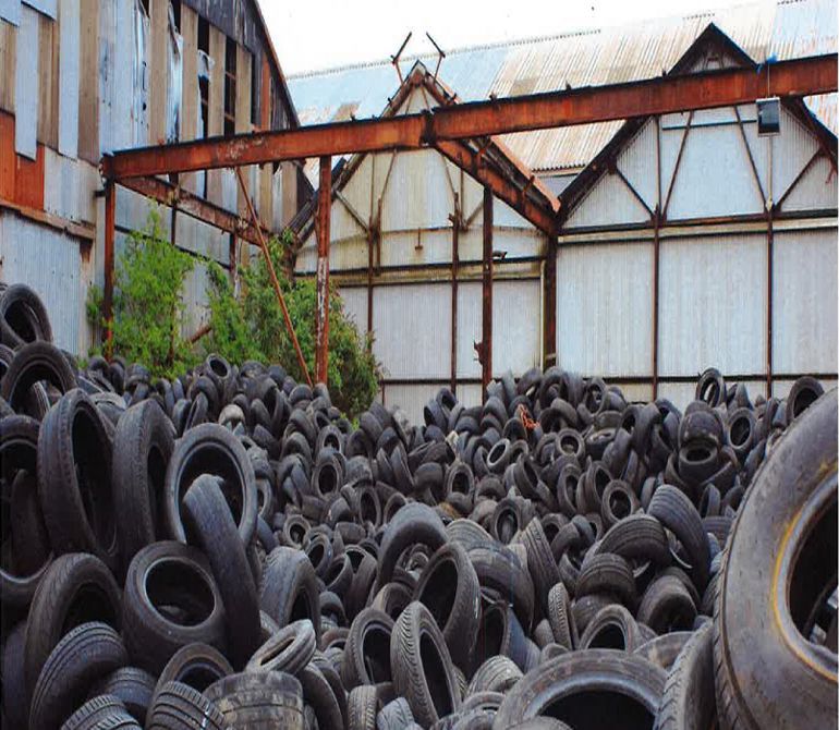 Lots of car tyres piled up outside a warehouse