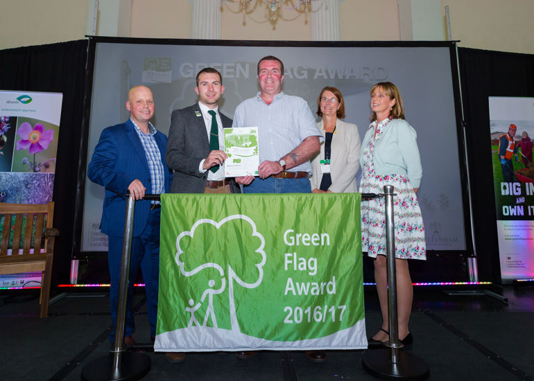 a group of 5 people stood behind a green flag awards 2016-17 banner