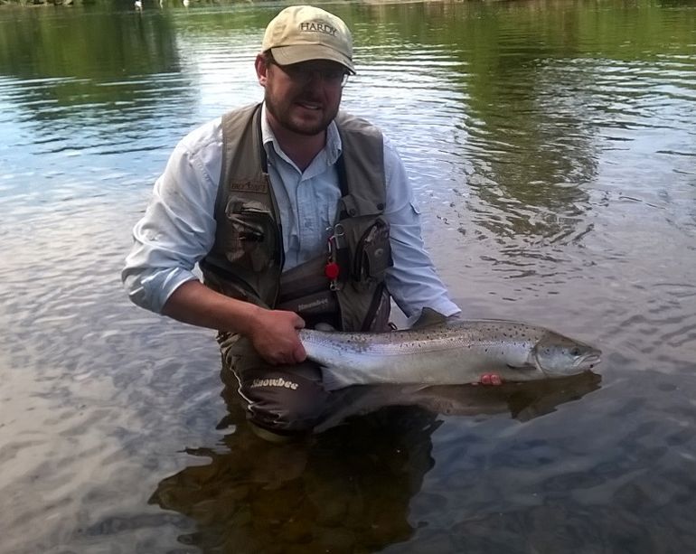 Angler holding a salmon while standing in the River Usk