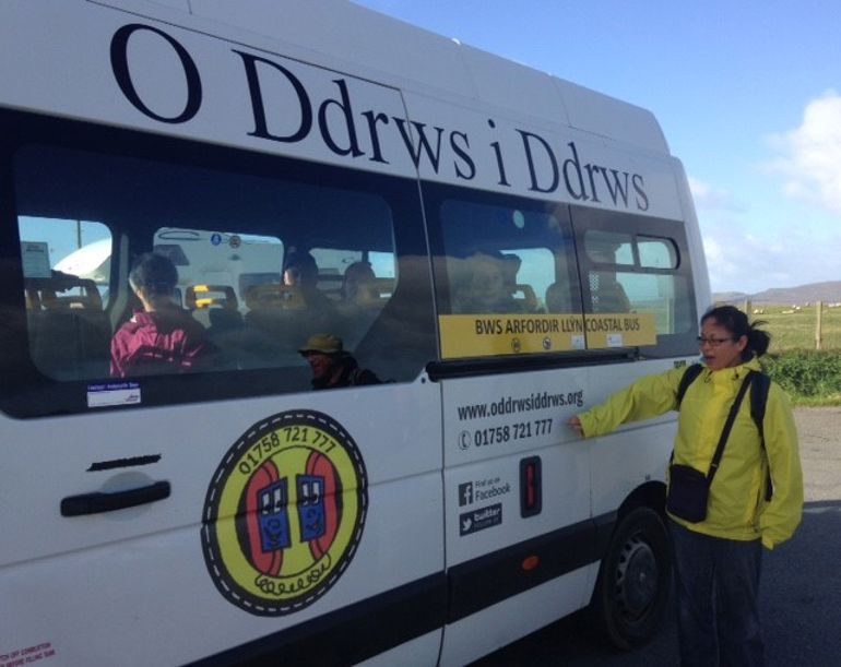 Woman standing next to the bus service to explore the coast of Llyn