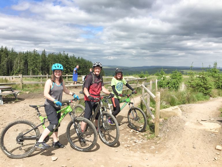 Three people on a bike trail standing with their bikes