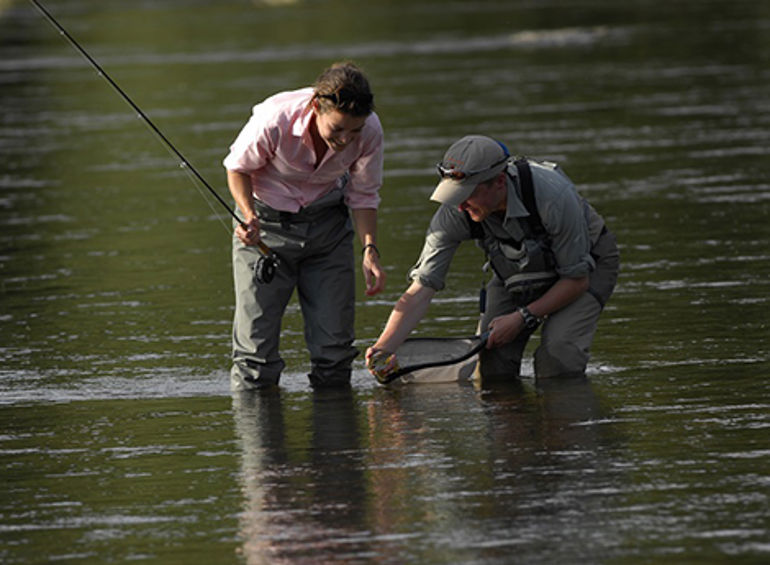 Two fishermen catching a fish in a river