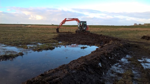 Machine digging low level banks of peat