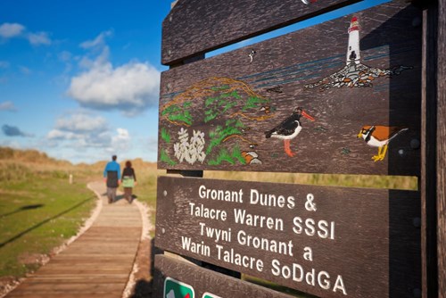 View of boardwalk at Gronant Dunes with Site of Special Scientific Interest sign prominant in foreground