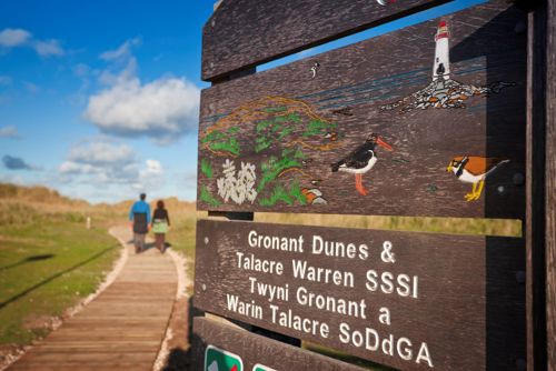 View of boardwalk at Gronant Dunes with Site of Special Scientific Interest sign prominant in foreground