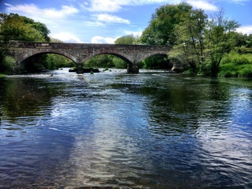 Pont garreg gyda bwâu addurniadol dros afon, gyda choed ar lannau’r afon